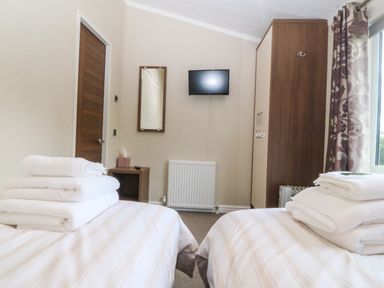 A bedroom with two beds and a television at Plas Marchog Lodge Rhoscefnhir near Pentraeth