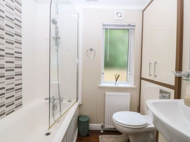 A bathroom with a shower, bathtub, and toilet at Plas Marchog Lodge Rhoscefnhir near Pentraeth