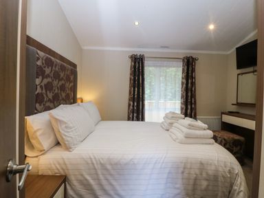 A bedroom with a bed and towels at Plas Marchog Lodge in Rhoscefnhir near Pentraeth