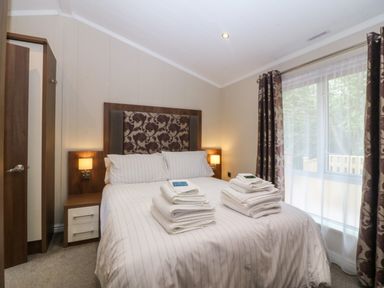 A bedroom with a bed and bedside table at Plas Marchog Lodge Rhoscefnhir near Pentraeth