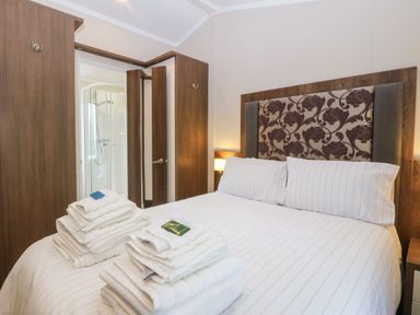 A bedroom with a bed and towels at Plas Marchog Lodge in Rhoscefnhir near Pentraeth