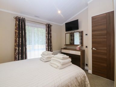 A bedroom with a bed and towels on top at Plas Marchog Lodge in Rhoscefnhir near Pentraeth