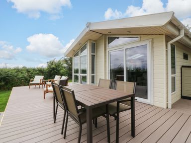 A deck with a table and chairs at Plas Marchog Lodge in Rhoscefnhir near Pentraeth