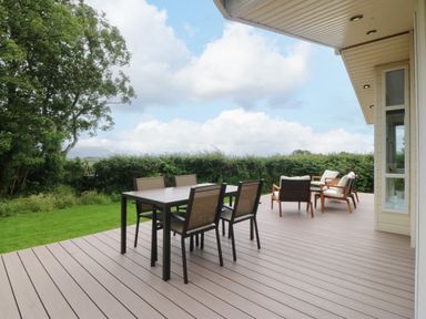 An outdoor patio with a table and chairs at Plas Marchog Lodge Rhoscefnhir near Pentraeth