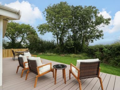 An outdoor patio with chairs and a table at Plas Marchog Lodge Rhoscefnhir near Pentraeth