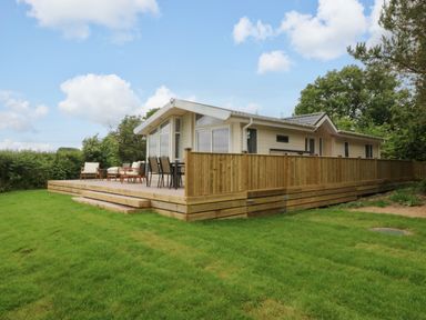 An outdoor area with a deck and seating at Plas Marchog Lodge Rhoscefnhir near Pentraeth