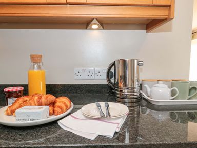 A kitchen countertop with croissants, butter, orange juice, and a kettle at Daisy Bank in Maugersbury near Stow-On-The-Wold