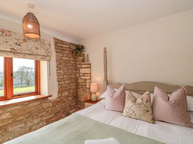 A bedroom with a bed and window at Daisy Bank in Maugersbury near Stow-On-The-Wold