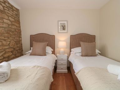 A bedroom with two beds and a nightstand at Daisy Bank Maugersbury near Stow-On-The-Wold