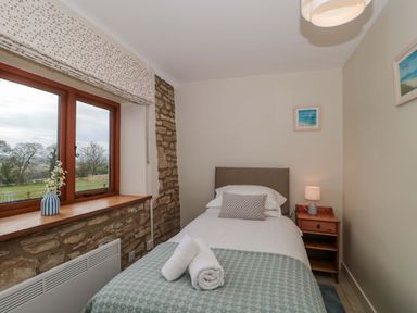 A bedroom with a bed and window at Daisy Bank in Maugersbury near Stow-On-The-Wold