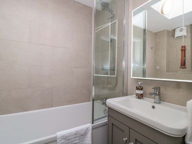 A bathroom with a bathtub, shower, and sink at Daisy Bank in Maugersbury near Stow-On-The-Wold