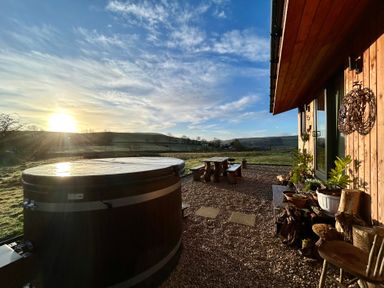 An outdoor area with a hot tub and wooden furniture at Harriet in Llangurig