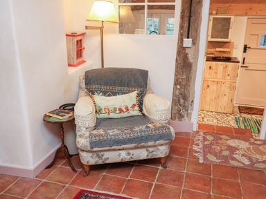 A living room with an armchair and a side table at The Hare & the Bumblebee Cottage