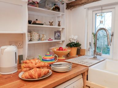 A kitchen with croissants on a plate and a fruit bowl at The Hare & the Bumblebee Cottage