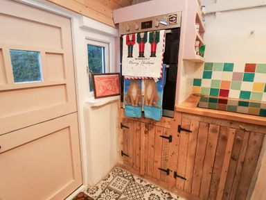 A kitchen with an oven and wooden cabinets at The Hare & the Bumblebee Cottage