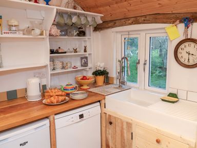 A kitchen with a sink, dishwasher, and shelves at The Hare & the Bumblebee Cottage