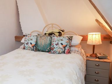 A bedroom with a bed and bedside table at The Hare & the Bumblebee Cottage
