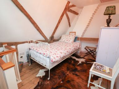 A bedroom featuring a bed with floral bedding at The Hare & the Bumblebee Cottage