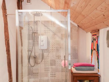 A shower area with tiles and towels at The Hare & the Bumblebee Cottage