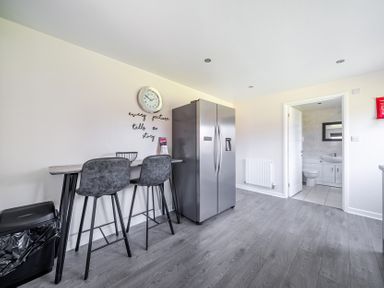 A kitchen with bar stools and refrigerator at Raven Lodge Near Brigg