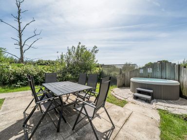 An outdoor area with a table, chairs and a hot tub at Raven Lodge Near Brigg
