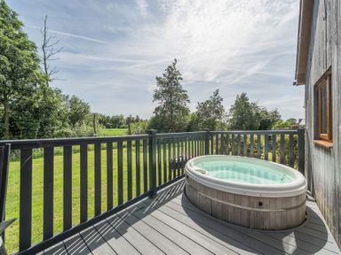 An outdoor area with a hot tub on a deck at Paddington Lodge near Brigg