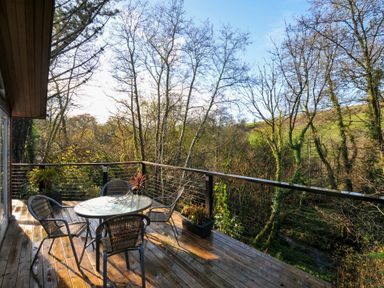 A terrace with a table and chairs overlooking trees at 6 Stonerush Valley Looe