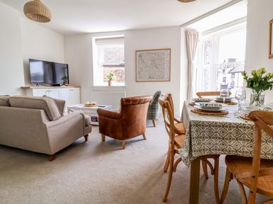 A living room with a television and dining area at The Old Bank Flat North Tawton
