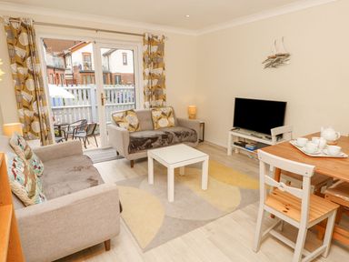 A living room with a sofa, table, and television at Harbour View Poole