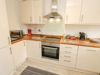 A kitchen with a microwave, oven, kettle, and kitchen cabinets at Harbour View Poole