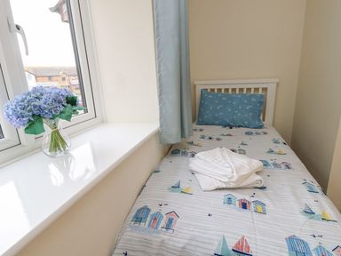 A bedroom with a single bed and a vase of flowers at Harbour View Poole