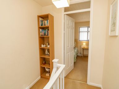 A hallway with a bookshelf and a door to another room at Poole Quay Cottage in Poole