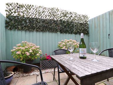 A garden with a table and wine at Poole Quay Cottage in Poole