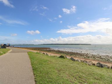 A coastal path with grass and people walking near the sea at Poole Quay Cottage in Poole