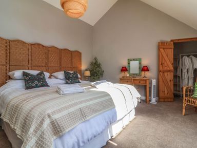 A bedroom with a bed and wardrobe at Captains Barn in Tiverton