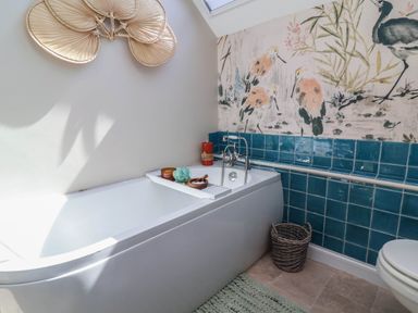 A bathroom with a bathtub and colorful tiles at Captains Barn Tiverton