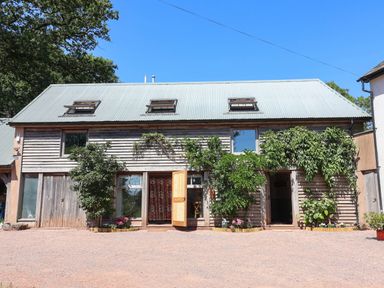 A wooden building with windows and plants at Captains Barn Tiverton