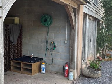 An outdoor area with a hose reel and potted plants at Captains Barn Cadeleigh near Tiverton