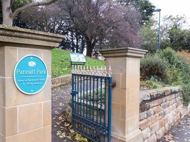 An entrance gate to Pannett Park with a sign in Whitby