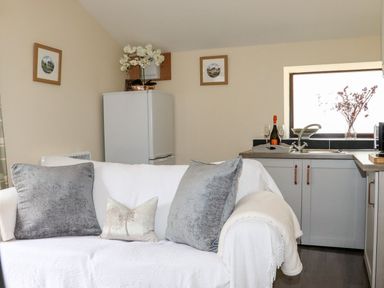 A kitchen with a sofa and refrigerator at Lannlyvri Lodge, Lanlivery near Lostwithiel
