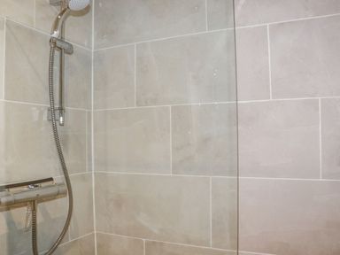 A shower area with tiled walls and a glass panel at Lannlyvri Lodge in Lanlivery near Lostwithiel