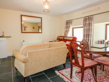 A living room with a sofa and dining table at Camellia Cottage Bodmin