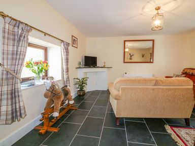 A living room with a television and a rocking horse at Camellia Cottage in Bodmin