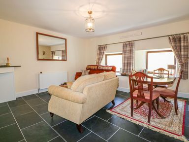 A living room with a sofa and dining table at Camellia Cottage in Bodmin
