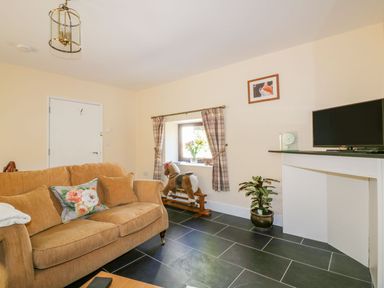 A living room with a sofa and television at Camellia Cottage in Bodmin