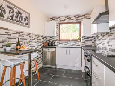 A kitchen with modern appliances and dining area at Camellia Cottage in Bodmin