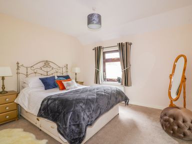 A bedroom with a bed and a dressing mirror at Camellia Cottage in Bodmin