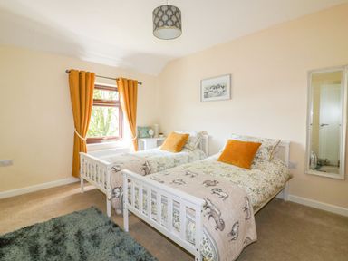 A bedroom with twin beds and a window at Camellia Cottage in Bodmin