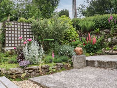 A garden with flowers and stone features at Camellia Cottage in Bodmin