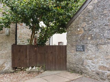 An outdoor area with a parking sign and a wooden fence at Camellia Cottage in Bodmin